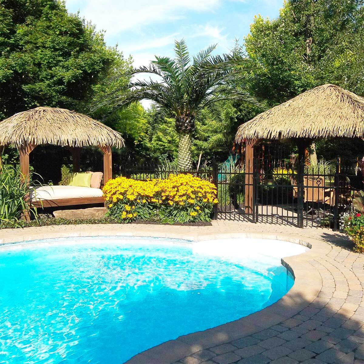 Deux pergolas en bois avec toiture en feuilles de palme synthétique Palmita de couleur naturelle, sur le bord d'une piscine creusée - Boutique Palmex